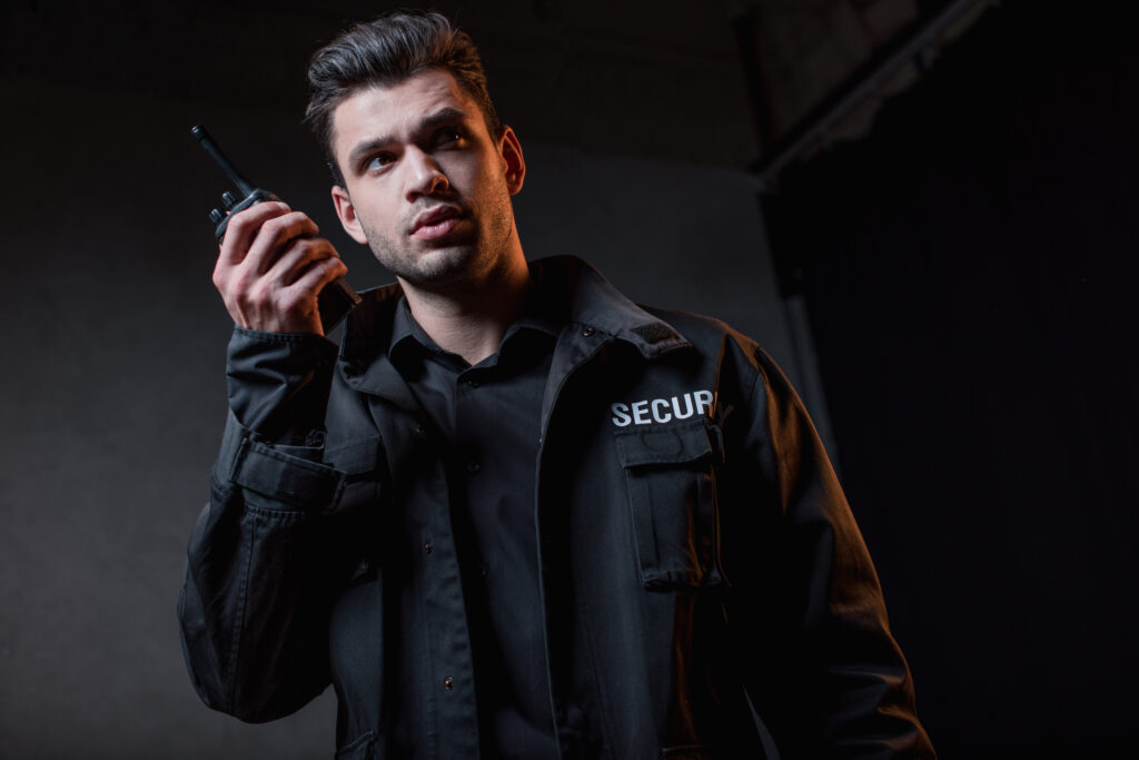 guard in black uniform holding walkie-talkie and looking away